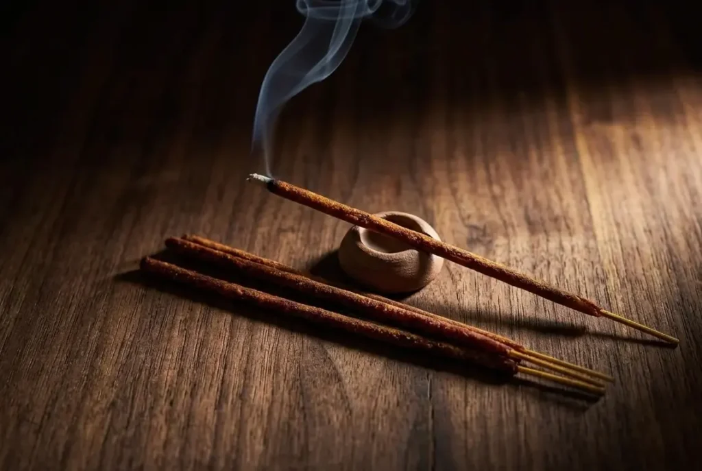 Best incense sticks gift for him UK with oud and dragon blood incense on dark wooden surface with clay incense holder