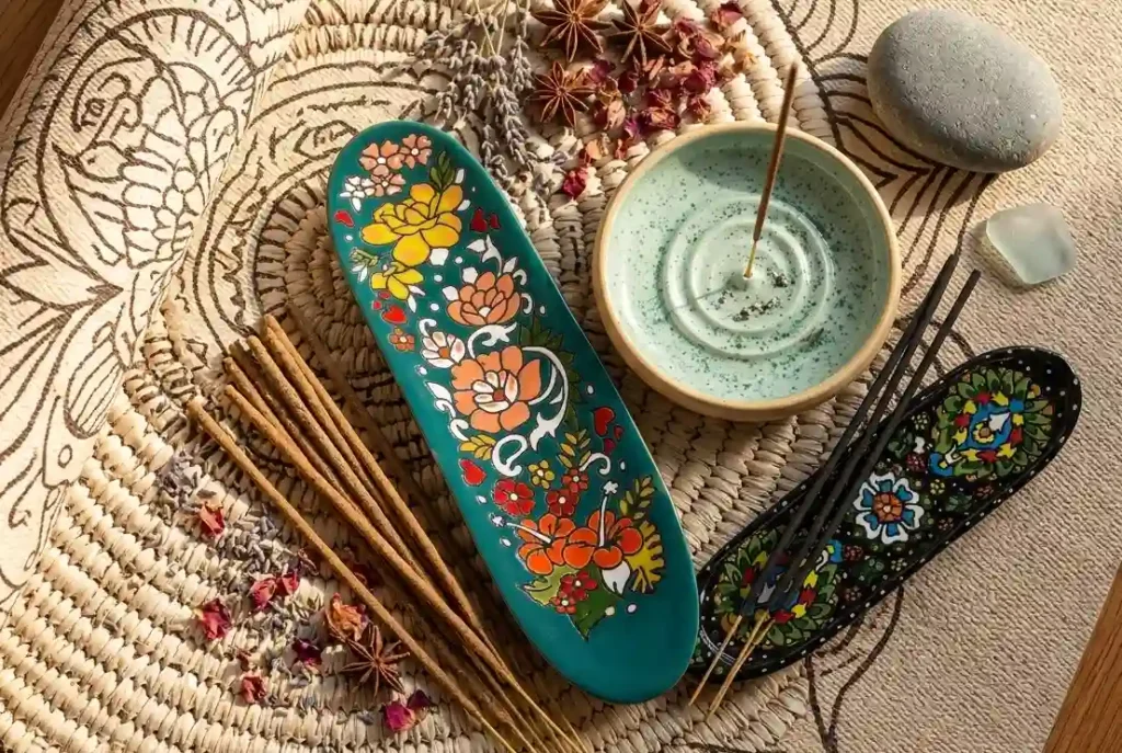 Clay incense holder paired with hand-rolled sandalwood and oud incense sticks on a yoga mat, wellness home setup UK